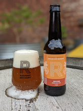 Load image into Gallery viewer, Runaway Brewery beer bottle and glass on a wooden surface with a blurred outdoor background
